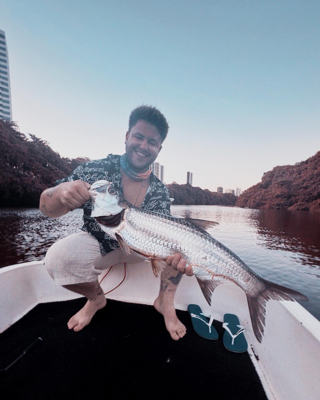 Mateus em um barco, segurando um peixe